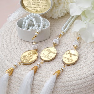 Puede incluir: Tres rosarios de perlas blancas con borlas doradas y dijes ovalados de oro personalizados. Los dijes tienen los nombres "Nicholas", "Blessed 6.11.2023" y "Jasmin Mi Bautizo 6.11.2023".