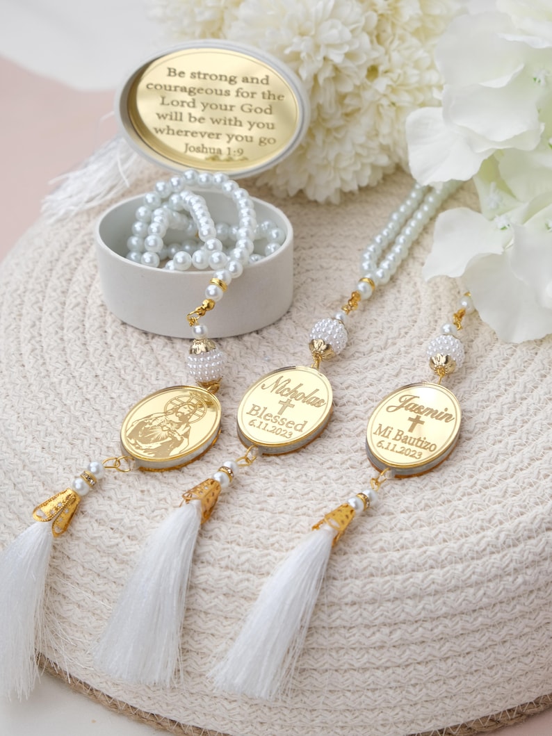 Puede incluir: Tres rosarios de perlas blancas con borlas doradas y dijes ovalados de oro personalizados. Los dijes tienen los nombres "Nicholas", "Blessed 6.11.2023" y "Jasmin Mi Bautizo 6.11.2023".