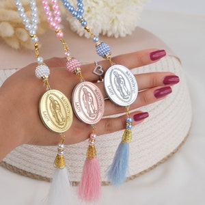 Puede incluir: Tres collares de cuentas con medallones dorados que representan la imagen de la Virgen Mar&iacute;a. Cada collar tiene un borla de un color diferente: blanco, rosa y azul.