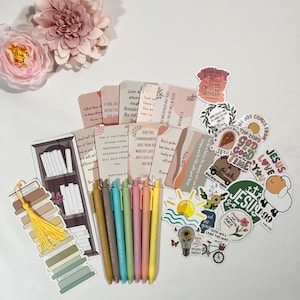 May include: A collection of stationery items including a tall bookmark with a bookshelf illustration, six pastel-colored retractable pens, several rectangular cards with printed religious text, and a variety of die-cut stickers with faith-based themes.