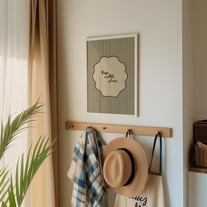 Hand drawn poster with the text "Keys wallet phone" inside a scalloped border on a neutral pinstripe background. Simple modern art used as Functional decor for Apartment decor or an Art for hall.