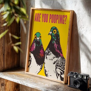 Bright pop art bright yellow poster of two pigeons staring forward,  funny toilet poster or guest bathroom art with text that reads “ARE YOU POOPING?”