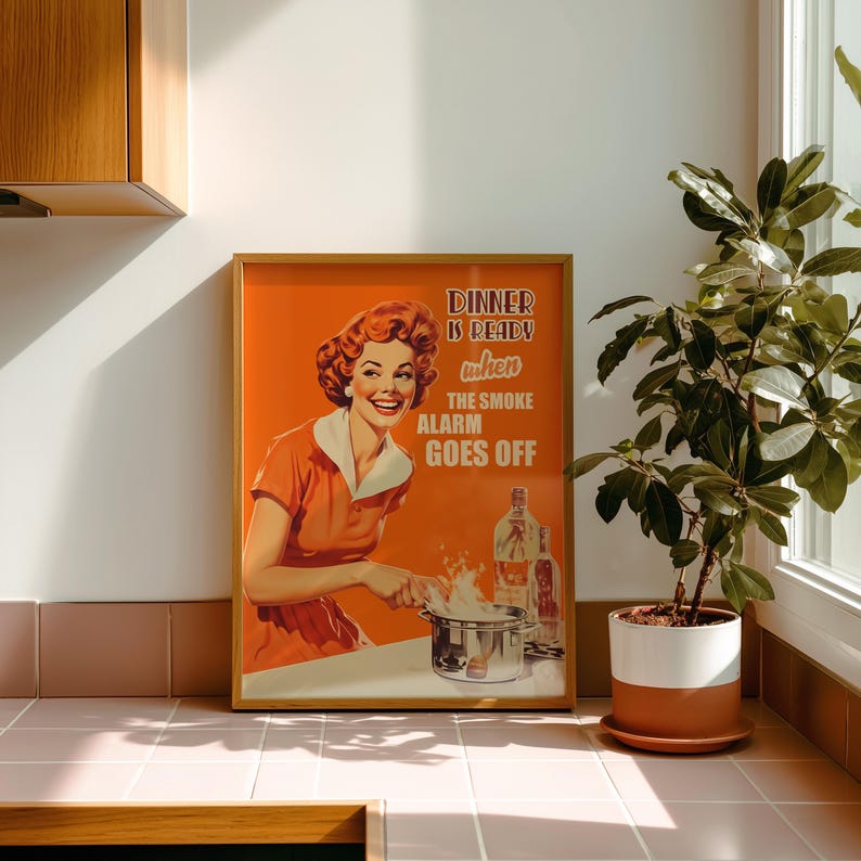 Retro style poster of a smiling housewife in an orange kitchen with a funny quote. Fun kitchen print in a 50s aesthetic for nostalgic decor.