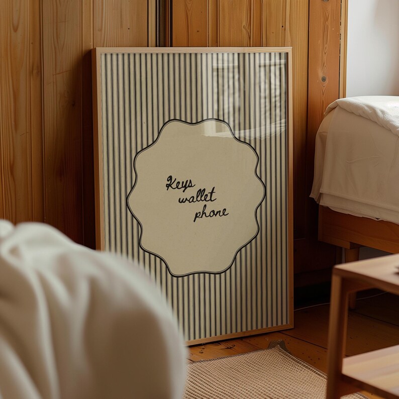 Hand drawn poster with the text "Keys wallet phone" inside a scalloped border on a neutral pinstripe background. Simple modern art used as Functional decor for Apartment decor or an Art for hall.