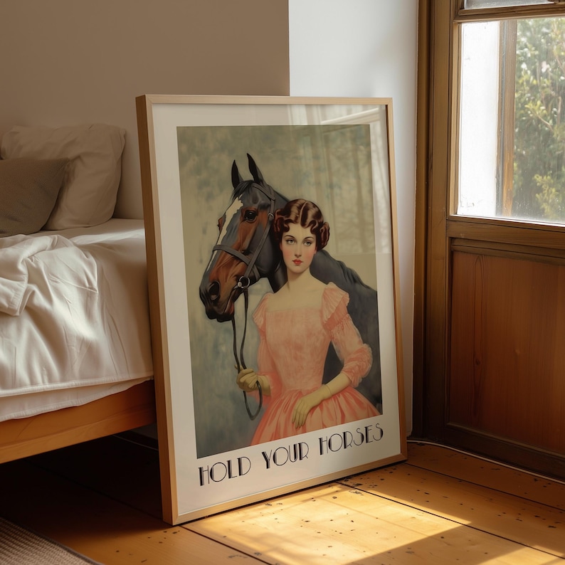 Vintage-style poster of a woman in a pink dress standing beside a horse, styled as equestrian wall art with country chic art and western decor charm, text reads “HOLD YOUR HORSES”