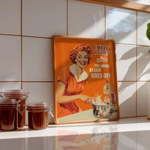 Retro style poster of a smiling housewife in an orange kitchen with a funny quote. Fun kitchen print in a 50s aesthetic for nostalgic decor.