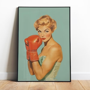 May include: A woman with blonde hair wearing a light blue dress and red boxing gloves. She is looking directly at the viewer with a serious expression.