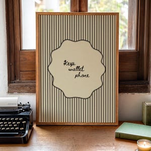 Hand drawn poster with the text "Keys wallet phone" inside a scalloped border on a neutral pinstripe background. Simple modern art used as Functional decor for Apartment decor or an Art for hall.