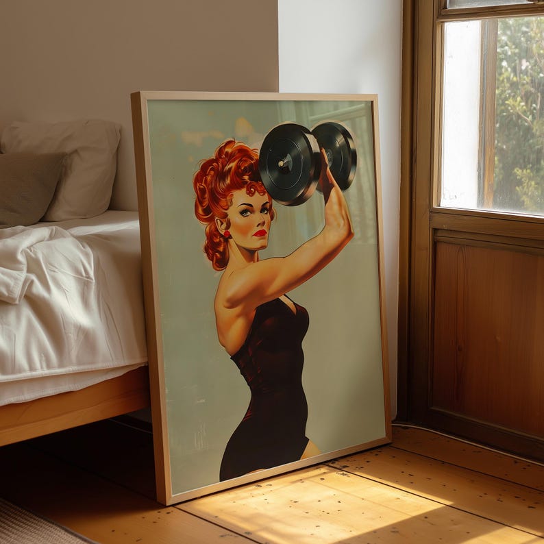 Vintage 1950s style pin-up girl art print featuring a strong woman with red hair lifting a heavy black dumbbell overhead. Retro fitness wall art showing a muscular woman in a black swimsuit, perfect for a vintage home gym decor, garage art, or mid-century modern aesthetic.