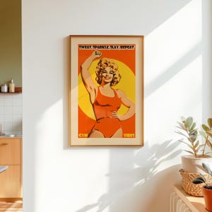 Retro gym art featuring an 80s style woman in an orange bodysuit flexing. Vibrant yellow sun background with the text Sweat Sparkle Slay Repeat. Maximalist dopamine decor for home gym walls.