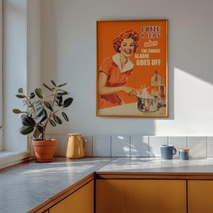 Retro style poster of a smiling housewife in an orange kitchen with a funny quote. Fun kitchen print in a 50s aesthetic for nostalgic decor.