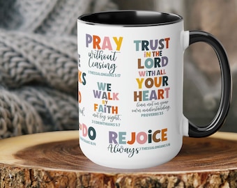 May include: White ceramic mug with a black handle and black rim. The mug features a colorful pattern of inspirational quotes and bible verses, including "Pray without ceasing", "Trust in the Lord with all your heart", "We walk by faith, not by sight", "Rejoice always".