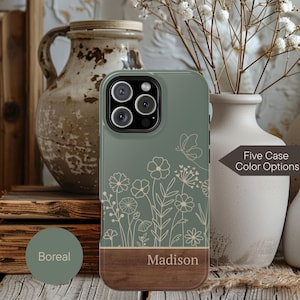May include: A sage green phone case with a floral design and a wooden bottom. The case features a butterfly and flower illustration. The name "Madison" is printed on the wooden section. The text "Five Case Color Options" is also visible.