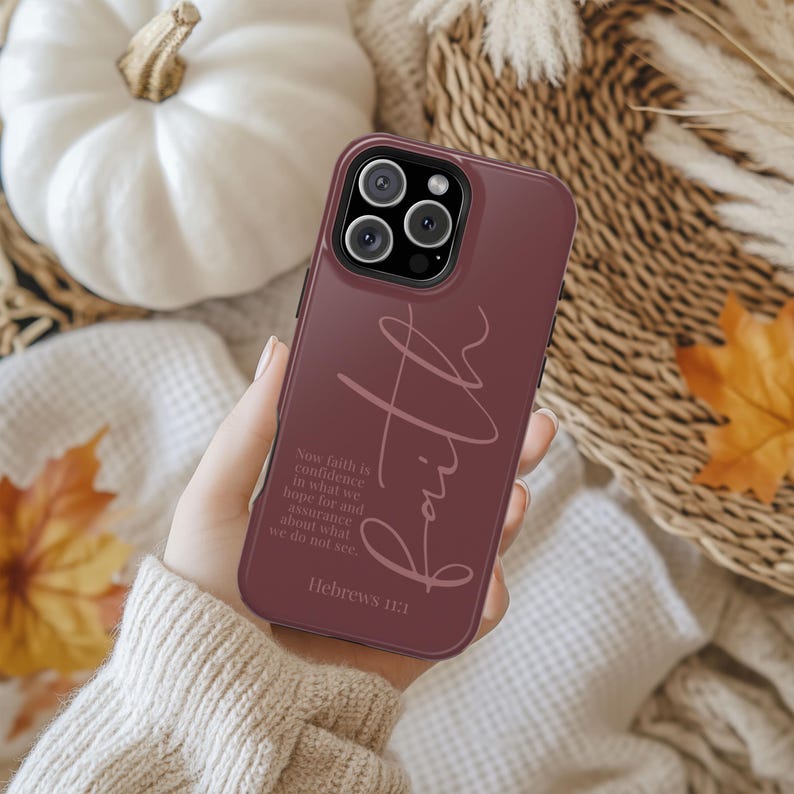 May include: A burgundy phone case with the word "Faith" in a cursive font. The case also features the text "Now faith is confidence in what we hope for and assurance about what we do not see. Hebrews 11:1."