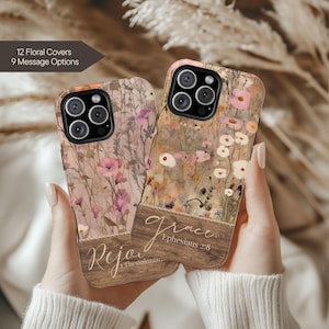 May include: Two floral phone cases with a wooden panel design. One case features the word "Rejoice" and the other says "Grace" with a Bible verse. The cases have a floral pattern in shades of pink, white, and brown.