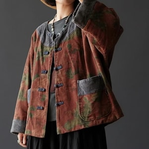 Può includere: Giacca color ruggine con un motivo screziato verde e marrone. La giacca ha un colletto e dettagli delle tasche in stile denim ed è chiusa con piccoli bottoni scuri. Le maniche sono lunghe e la giacca ha due tasche anteriori.