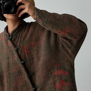 May include: A brown and red patterned jacket with a mandarin collar and frog closures. The long-sleeved jacket has a textured appearance and a subtle floral design. The jacket is made of a soft, comfortable material.
