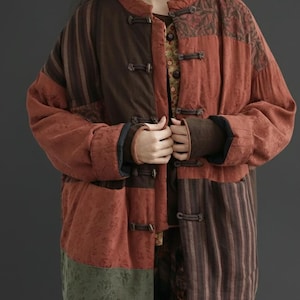 May include: A patchwork jacket in shades of brown, rust, and olive green. The jacket features a mandarin collar, toggle closures, and a mix of patterned and striped fabrics. The sleeves have dark brown cuffs.