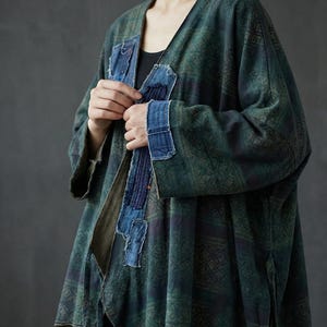May include: A long, open-front jacket in shades of green and blue with a geometric pattern. The jacket features denim patches on the front and sleeves. The sleeves are long and the jacket appears to be made of a soft, flowing fabric.