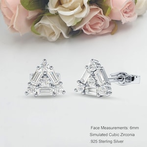 May include: Silver triangle stud earrings with cubic zirconia stones. Face measurements: 6mm. Simulated Cubic Zirconia. .925 Sterling Silver.