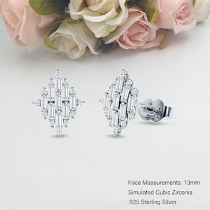 May include: A pair of silver earrings with a geometric design featuring a cluster of baguette-shaped cubic zirconia stones. The earrings are 13mm in size and are made of .925 sterling silver.