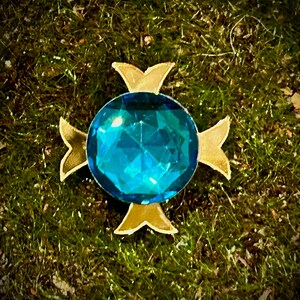May include: A blue gemstone set in a gold four-pointed star design.
