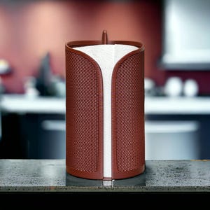 Pode incluir: Um porta-toalhas de papel cilíndrico castanho-avermelhado com um design tecido, num ambiente de cozinha. Apresenta uma secção vertical de toalhas de papel brancas. A parte superior é curva e tem uma pequena pega.