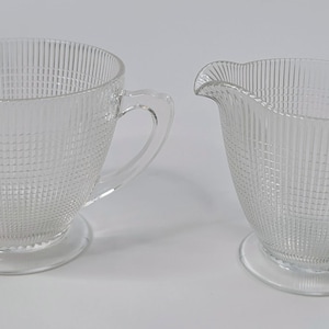 Peut inclure: Un ensemble de crémier et de sucrier en verre transparent avec un motif côtelé. L'ensemble est parfait pour servir du café ou du thé.