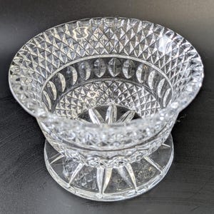 Op de afbeelding: Een glazen kom met een geslepen glasontwerp. De kom heeft een brede, uitlopende rand en een voet.