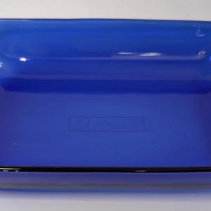 Puede incluir: Una fuente rectangular de vidrio azul cobalto con esquinas redondeadas y un borde negro. La fuente está vacía. La fuente mide aproximadamente 30 cm de largo y 20 cm de ancho.
