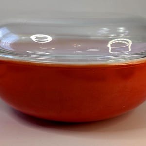 Peut inclure: Un saladier rond en céramique rouge avec un couvercle en verre transparent. Le bol a une finition brillante et un bord légèrement évasé. Le couvercle en verre s'adapte parfaitement, créant un ensemble complet d'articles de cuisine. Ce bol de style vintage est adapté au service ou au stockage.