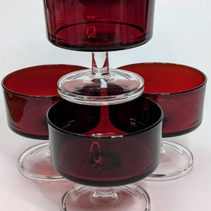 May include: Set of four red glass dessert dishes with clear glass stems and bases. The dishes are stacked on top of each other.