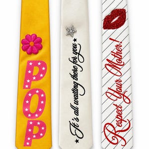 May include: Three neckties displayed side-by-side. The left tie is yellow with a pink flower and the word POP in pink with white stars. The centre tie is off-white with a crystal star and the text It's all waiting there for you. The right tie is white with black diagonal stripes, a red glitter lip graphic, and the text Respect Your Mother!