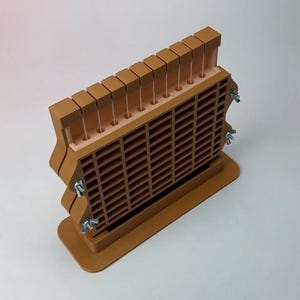 May include: A brown wooden tool with a grid-like structure and a series of vertical slots. The tool has a rectangular base and is secured with metal wing nuts. The top features a row of small, square blocks.