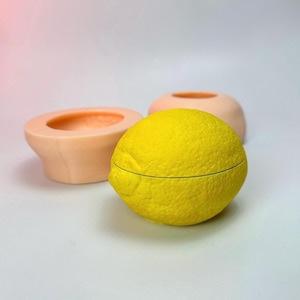 May include: A yellow lemon-shaped box with a textured surface. The box is open and the inside is visible. The box is sitting on a white surface.