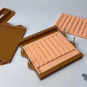 Puede incluir: Un juego de moldes marr&oacute;n y melocot&oacute;n para manualidades. El juego incluye un molde rectangular con varios patrones texturizados, una tapa y un molde separado. Los moldes est&aacute;n dise&ntilde;ados para crear elementos decorativos.