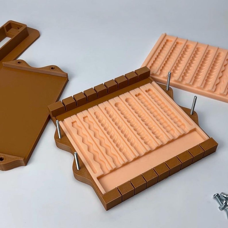 Puede incluir: Un juego de moldes marr&oacute;n y melocot&oacute;n para manualidades. El juego incluye un molde rectangular con varios patrones texturizados, una tapa y un molde separado. Los moldes est&aacute;n dise&ntilde;ados para crear elementos decorativos.