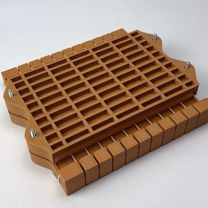 May include: A brown, rectangular, multi-compartment organizer with a grid-like top. The organizer has a tray-like design with a series of small, rectangular openings. Metal screws secure the top and bottom sections. The item is designed for organizing small items.