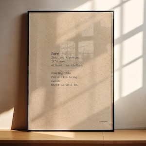 Puede incluir: Impresión artística enmarcada con la palabra "Bare" y un poema en fuente de máquina de escribir sobre un fondo beige. El marco negro está sobre una superficie de madera, con luz solar y sombras. El texto incluye el nombre del autor, Juniper.