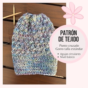 May include: A knitted beanie in a mix of pastel colours, including blue, purple, and yellow. The hat features a textured stitch pattern and is displayed with knitting needles. The image also includes text in Spanish: "PATRÓN DE TEJIDO".