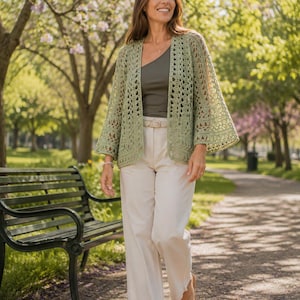 Puede incluir: Un cárdigan de ganchillo abierto en color verde salvia con mangas anchas de tres cuartos, usado sobre un top verde oliva de un solo hombro y pantalones anchos color crema con cinturón a juego y sandalias de tiras.
