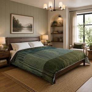 May include: A dark wood bed frame features a textured, quilted comforter in shades of forest green and olive. Two white pillows rest against the headboard. The bed is positioned in a room with light green walls, a jute rug, and a wooden nightstand.
