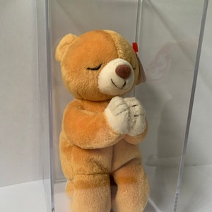 May include: A tan and brown plush praying bear with a red and white Ty tag. The bear is in a clear plastic display case.