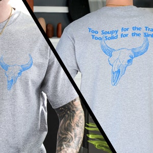 May include: Gray t-shirt with a blue bull skull graphic on the front and the text "Too Soupy for the Trash Too Solid for the Sink" on the back.
