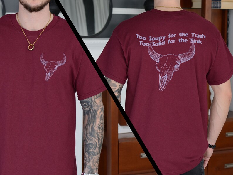 May include: A maroon t-shirt with a white bull skull graphic on the front and the text "Too Soupy for the Trash Too Solid for the Sink" on the back.