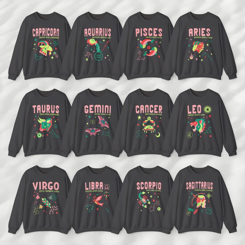 May include: Twelve gray sweatshirts with colorful zodiac signs and names. The signs are Capricorn, Aquarius, Pisces, Aries, Taurus, Gemini, Cancer, Leo, Virgo, Libra, Scorpio, and Sagittarius.