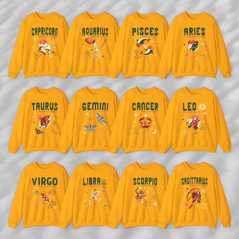 May include: Twelve yellow sweatshirts with zodiac signs printed on the front. Each sweatshirt features a different zodiac sign with a unique illustration and text. The signs include Capricorn, Aquarius, Pisces, Aries, Taurus, Gemini, Cancer, Leo, Virgo, Libra, Scorpio, and Sagittarius.