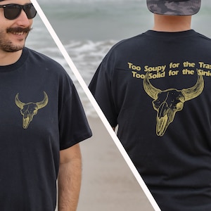 May include: Black t-shirt with a gold bull skull graphic on the front and the text "Too Soupy for the Trash Too Solid for the Sink" with a gold bull skull graphic on the back.