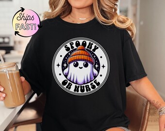 Może przedstawiać: Czarny T-shirt z białym kołem graficznym przedstawiającym kreskówkowego ducha w pomarańczowo-białym kapeluszu. Wewnątrz koła znajduje się tekst "Spooky or Nurse".