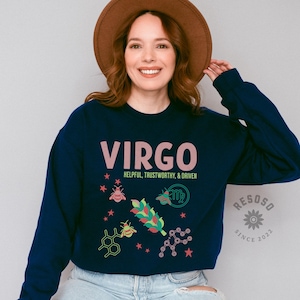 May include: Navy blue sweatshirt with a pink "VIRGO" graphic, the text "HELPFUL, TRUSTWORTHY, & DRIVEN", and a stylized Virgo zodiac symbol with bees and stars. The sweatshirt also has a small logo with the text "RESOSO SINCE 2022".
